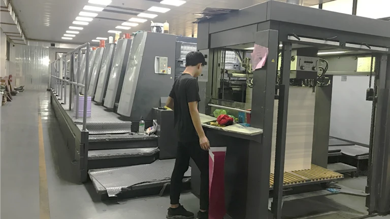 Worker operating a printing machine in a factory production line