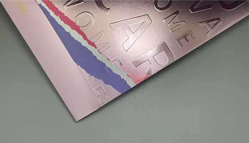 Embossed silver surface with debossed letterforms and tactile finish.