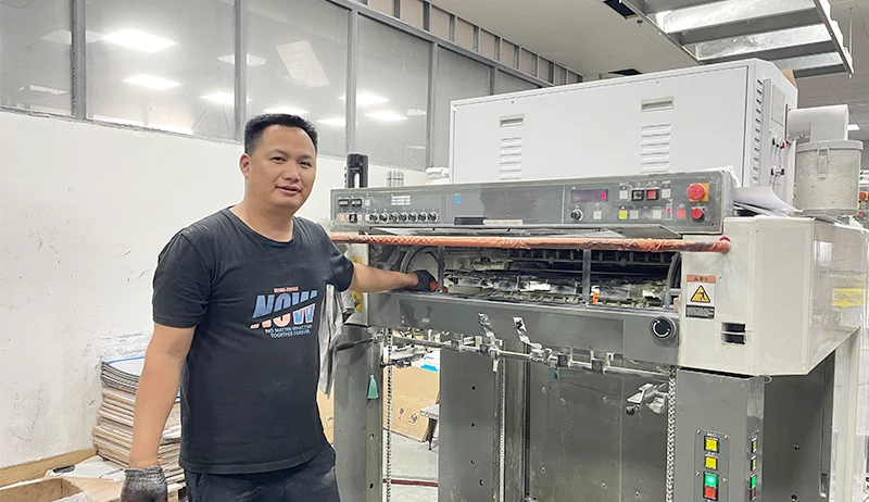 Factory worker using Komori 4-color printing press for paper stock