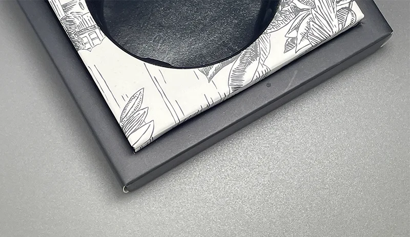 A printed cardboard insert with a curved cutout for holding beauty items.