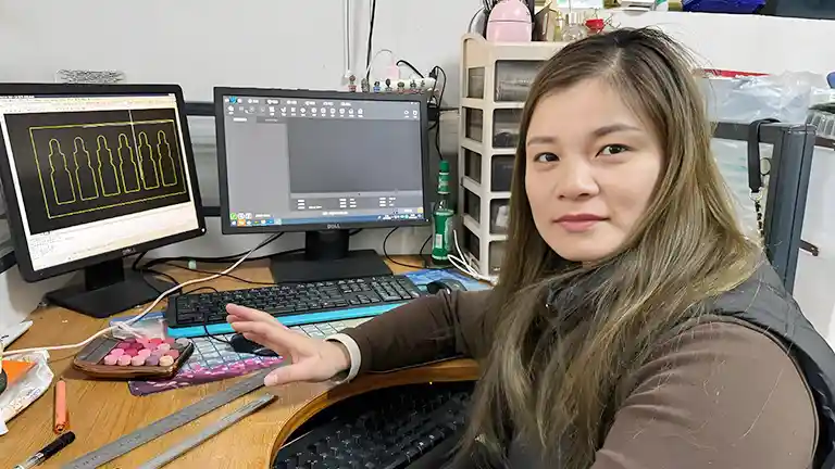 Designer working on packaging software, surrounded by tools and monitors