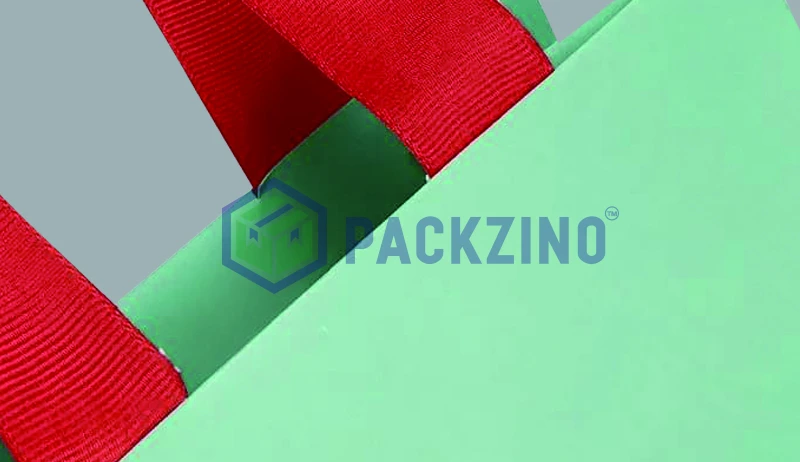 Red polyester handle taped onto green paper bag top edge