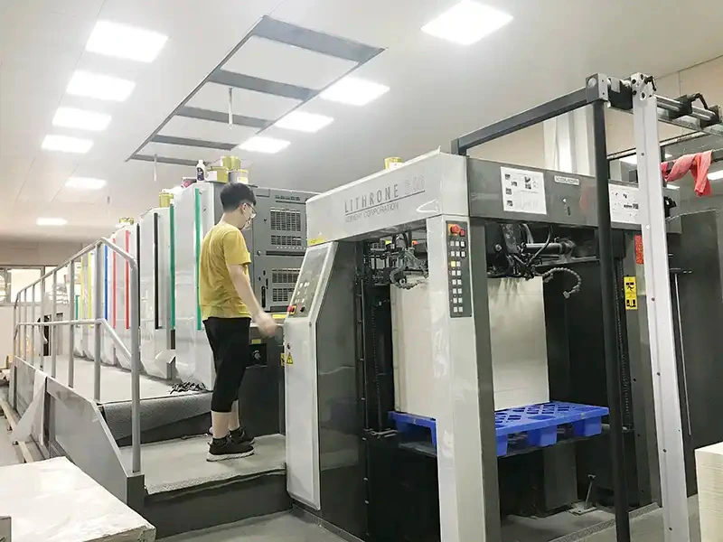 Operator managing an automated printing press used for manufacturing custom makeup boxes