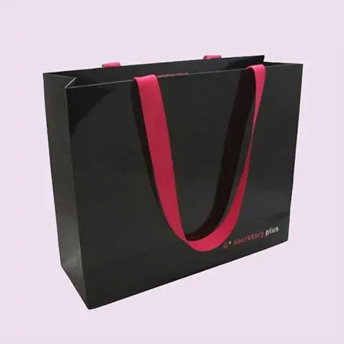 Custom paper shopping bag with pink ribbon handles for ecommerce retail packaging.