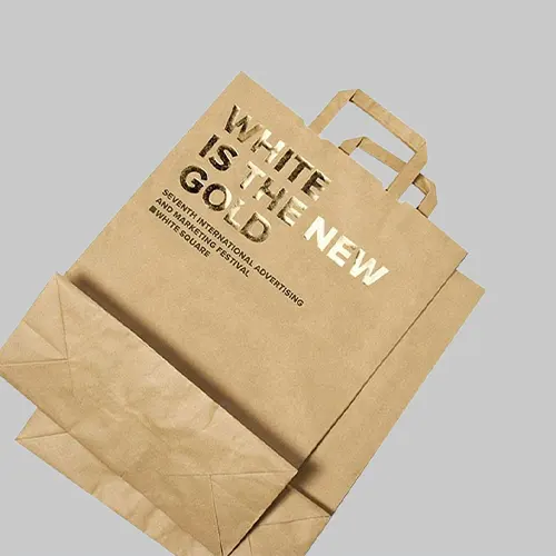 Eco-friendly kraft shopping bag with flat handles and gold foil text for sustainable retail.