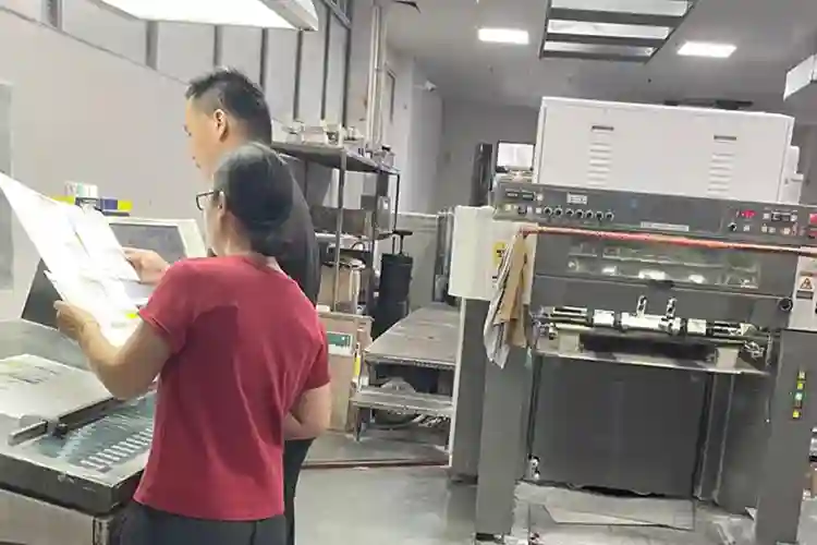 Workers inspecting print sheets during rigid box production