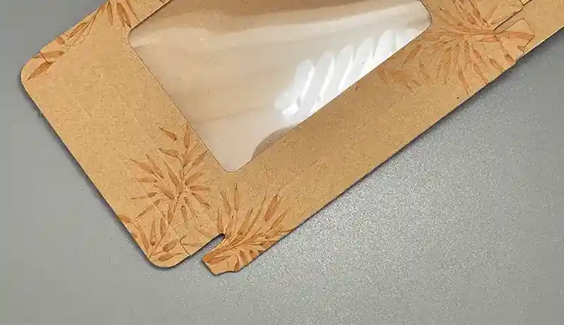 Kraft paperboard box with clear PET window and printed leaf design.