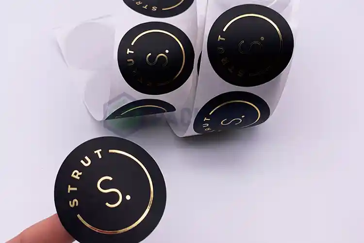 Black round labels with gold foil stamping on roll