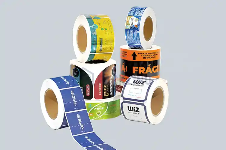 Multiple rolls of custom printed labels in different colors and designs on gray background