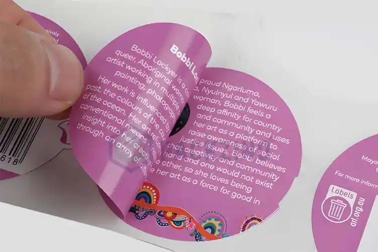 A close-up of a removable label being peeled off, showing printed content on both sides